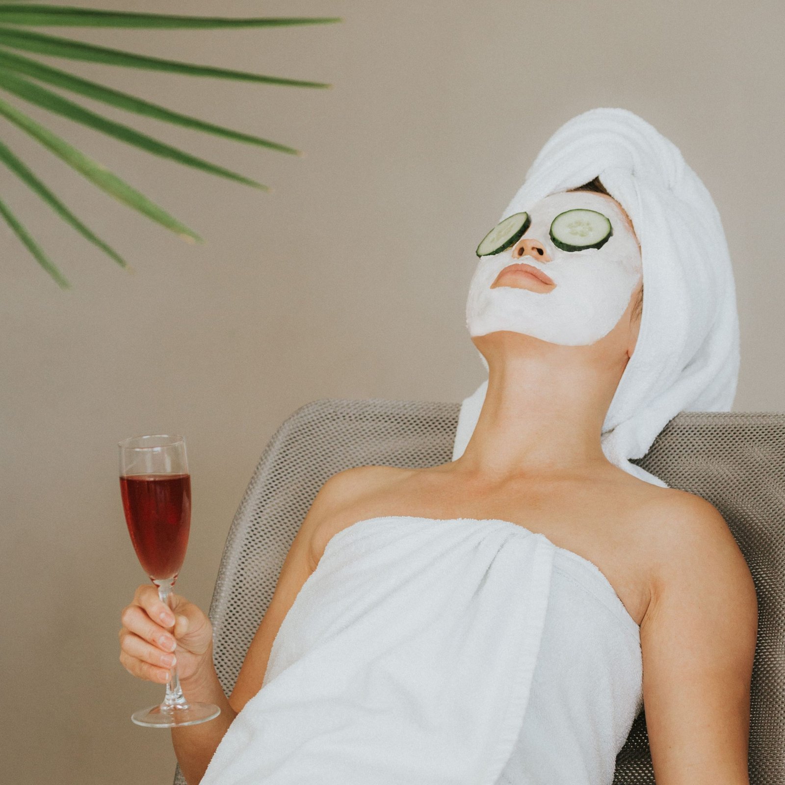 Woman enjoying a spa day with face mask, wine, and relaxation. Perfect for wellness themes.