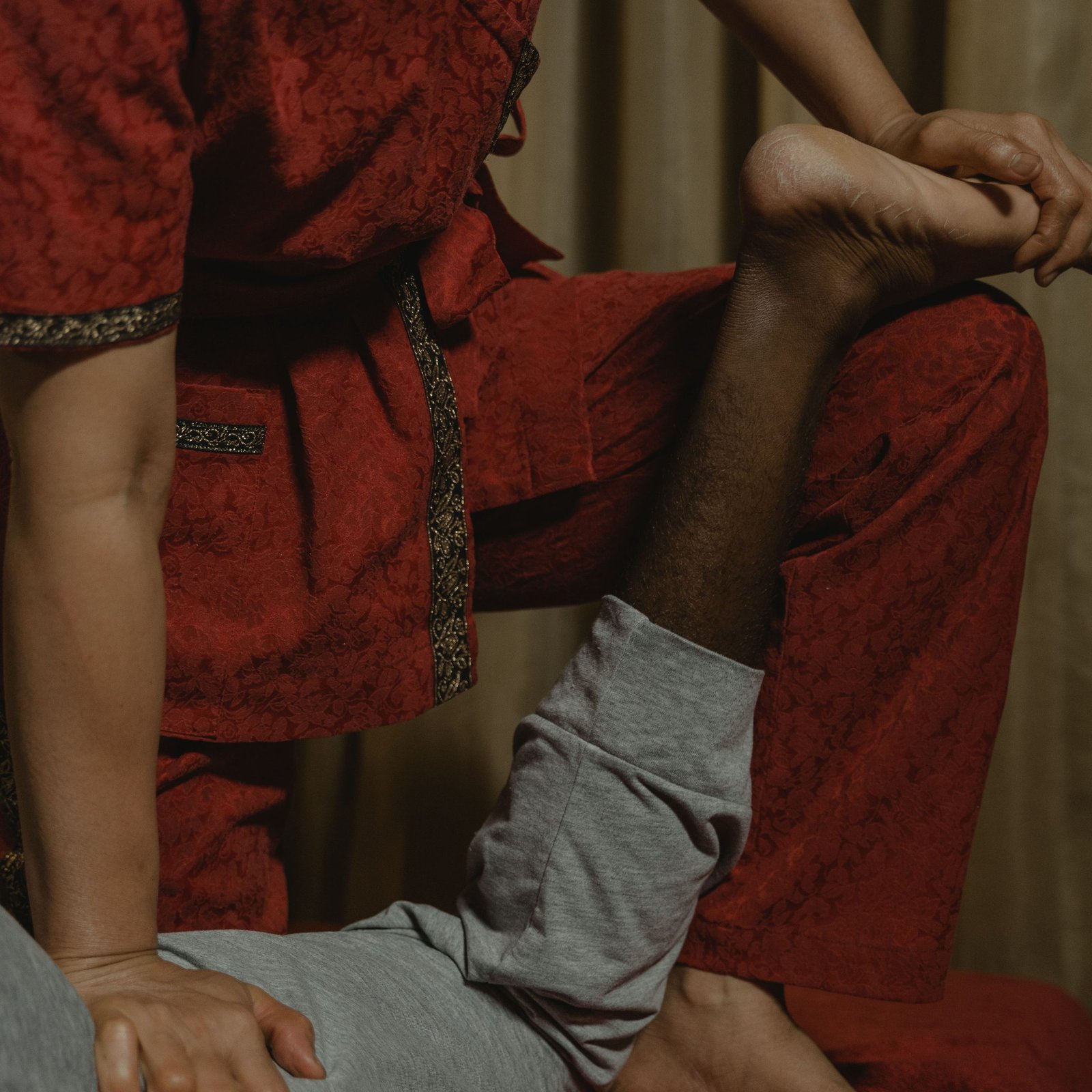 Therapist in red attire performing a leg massage, focusing on wellness and relaxation.
