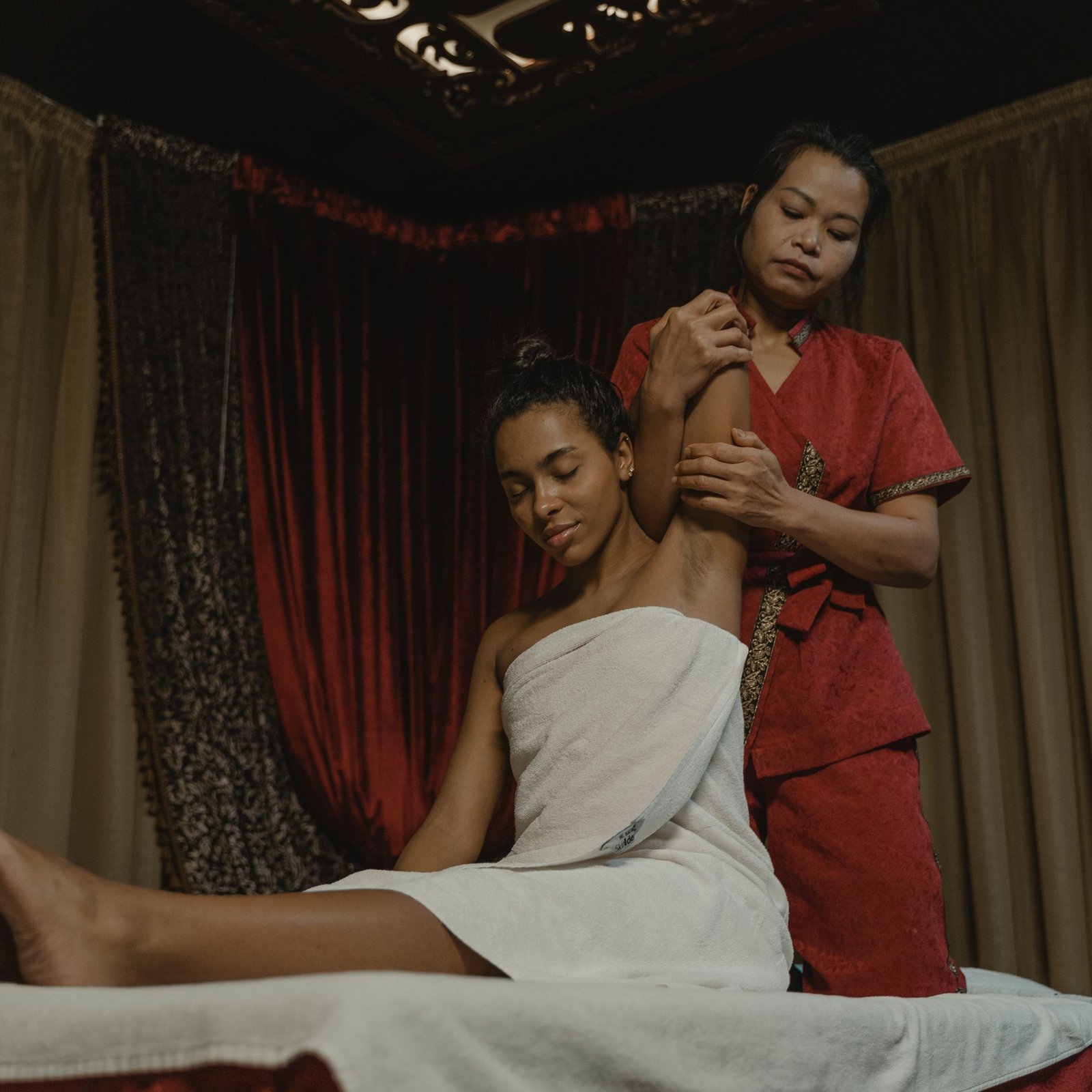 A soothing spa session with a woman receiving a massage indoors, wrapped in a towel.