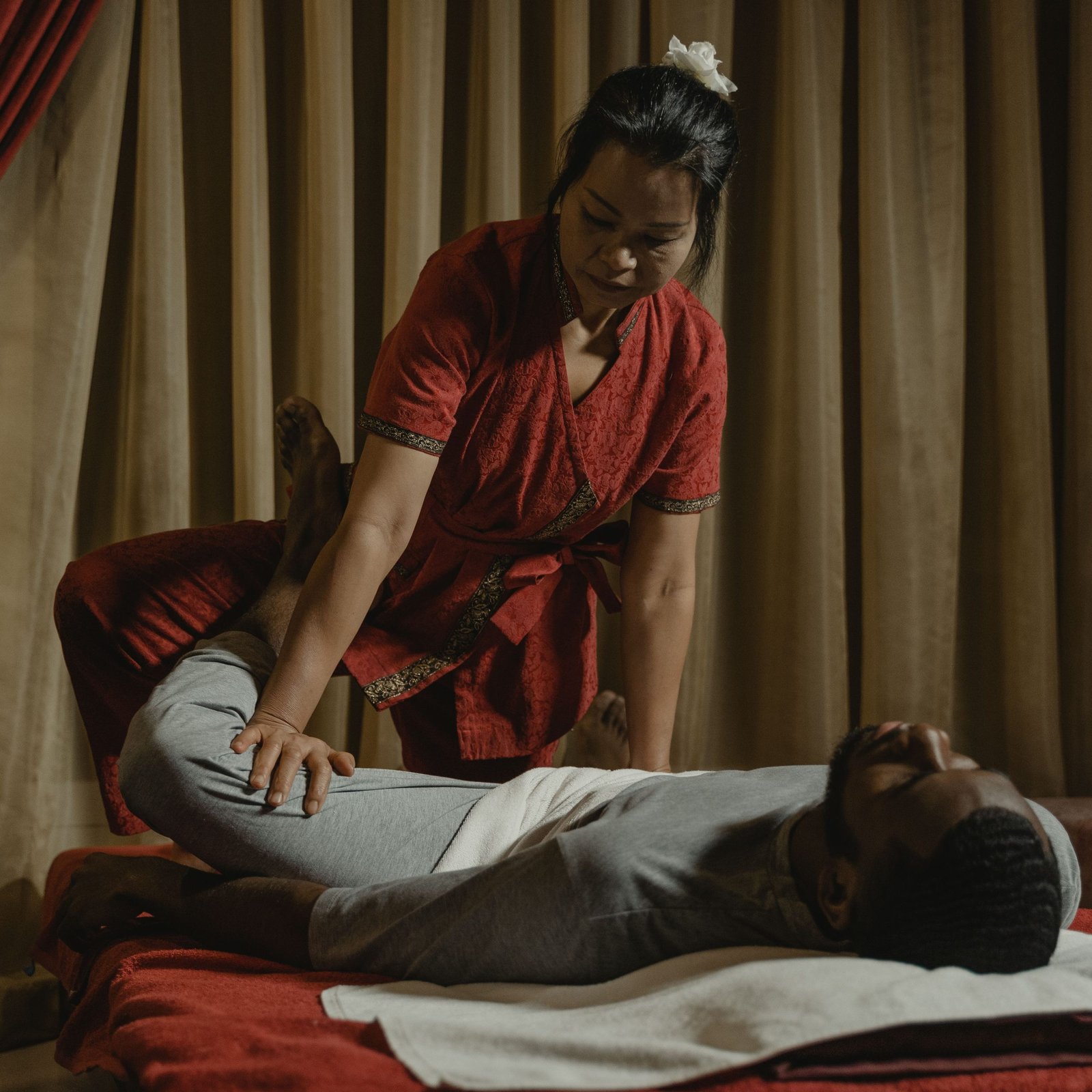 Professional therapist performing leg stretch on client in a serene massage room setting.